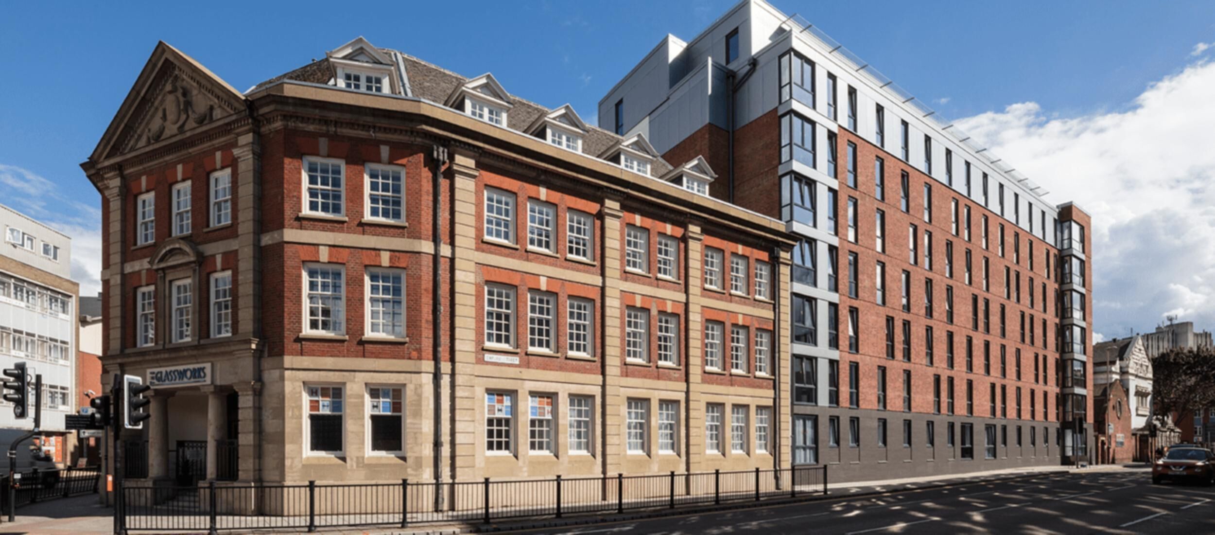 A multi-story building with a mix of traditional and modern architectural styles, featuring a prominent corner entrance and a large glass facade.