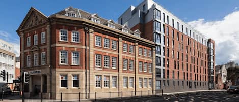 A multi-story building with a mix of traditional and modern architectural styles, featuring a prominent corner entrance and a large glass facade.