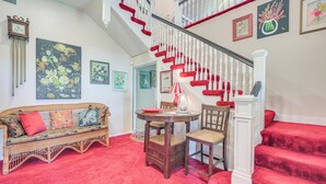 A staircase with red steps and white balusters, a wicker sofa with colorful cushions, a round wooden table with chairs, and a red carpeted floor. - Hot Tub & Sauna! 2 Wichita Falls Units 1 Mi to AFB (Wichita Falls)