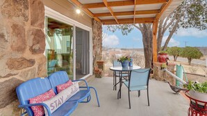 A covered patio with stone walls, a glass door, blue chairs, a table, and a potted plant. - Hot Tub & Sauna! 2 Wichita Falls Units 1 Mi to AFB (Wichita Falls)