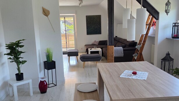 Ein modernes Wohnzimmer mit einem Holzespeisetisch, weißen Hocker, einer Couch und einer Treppe.