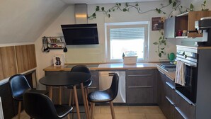 Eine moderne Küche mit Essbereich, inklusive Kaffeemaschine, Brotbackmaschine und Geschirrspüler.