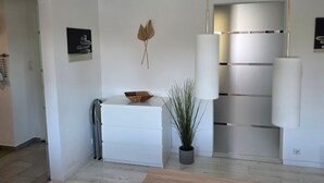 Ein modernes Interieur mit einem weißen Schminktisch, einer Topfpflanze und einer Pendelleuchte.
