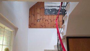 Eine Treppe mit hölzernem Geländer und rotem Sicherheitsseil, die zu einer Aussichtsplattform mit Blick auf eine Küstenlandschaft führt.