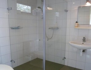 Ein Badezimmer mit Duschkabine, Waschbecken und Spiegel.