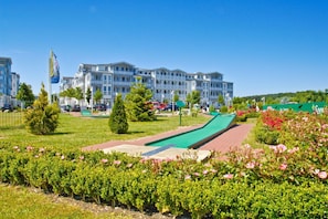 Ein Hotel mit Pool, Rasen und Blumenbeeten.