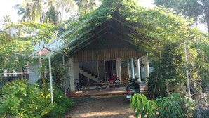 Una casa petita amb un porxo, una escala i una moto aparcada a l'exterior.