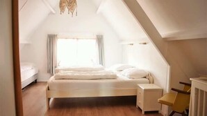 A bedroom with a bed, bedside table, chair, and a window with curtains. - Holiday Home 3 Minutes from Beach in Domburg - Ooststraat 16 (Domburg)