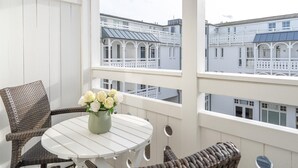 A balcony with wicker furniture, a white table, and a vase of flowers. - Kompakte Ferienwohnung im Seepark Sellin mit Balkon (Sellin)