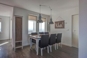 A dining area with a table, chairs, and pendant lights. - Stylish Apartment in Ouddorp for 6 (Ouddorp)