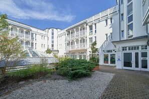 A multi-story building with balconies, a greenhouse, and a gravel courtyard. - schöne Ferienwohnung in Sellin mit Balkon (Sellin)