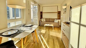 Ett modernt hotellrum med en matplats, soffa och utsikt genom ett stort fönster.