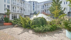 Ein Innenhof mit einem Gebäude, das Balkone und ein Gewächshaus besitzt.