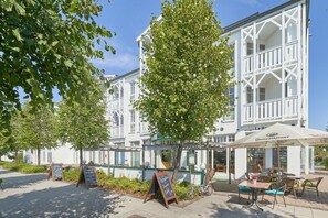 Un edificio blanco con balcones, mesas al aire libre y un letrero que dice 'Benedikiner'.