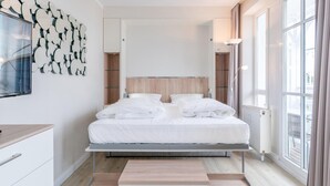 Un dormitorio moderno con cama, una obra de arte en la pared, una ventana y vistas al exterior.