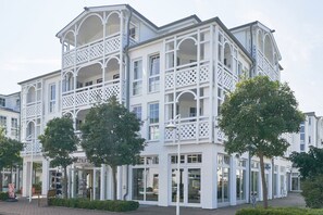 Un immeuble à plusieurs étages doté de balcons, de grandes fenêtres et d’un magasin au rez-de-chaussée.