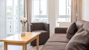 Ein modernes Wohnzimmer mit einer Couch, einem kleinen Tisch und einer Vase mit Blumen.
