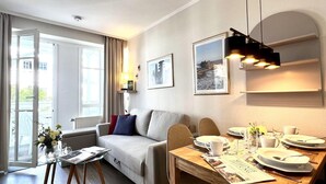 Ett modernt hotellrum med en soffa, ett matbord och utsikt genom fönstret.