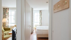 Ett hotellrum med en säng, en stol, ett bord och en lampa.