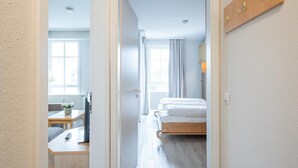 Een hotelkamer met een bed, een bureau met een computer, een stoel en een raam.