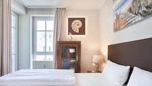 Ein Hotelzimmer mit einem großen Bett, einem Holzkasten, einem Nachttisch mit Lampe und einem Wandbild.