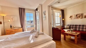 Hotellihuone, jossa on sänky, työpöytä, tuoli, sohva ja ikkuna, jossa on verhot.