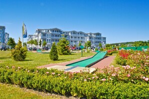 Ein Hotel mit Schwimmbad, Rasen und Blumenbeeten.
