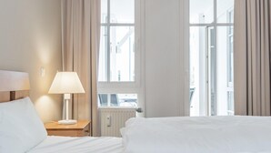 Ein Hotelzimmer mit Bett, Nachttischlampe, Fenster und Heizkörper.