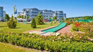 Ein Hotel mit Schwimmbad, Rasen und Blumenbeeten.