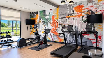 Een sportschool met loopbanden, hometrainers en gewichten.