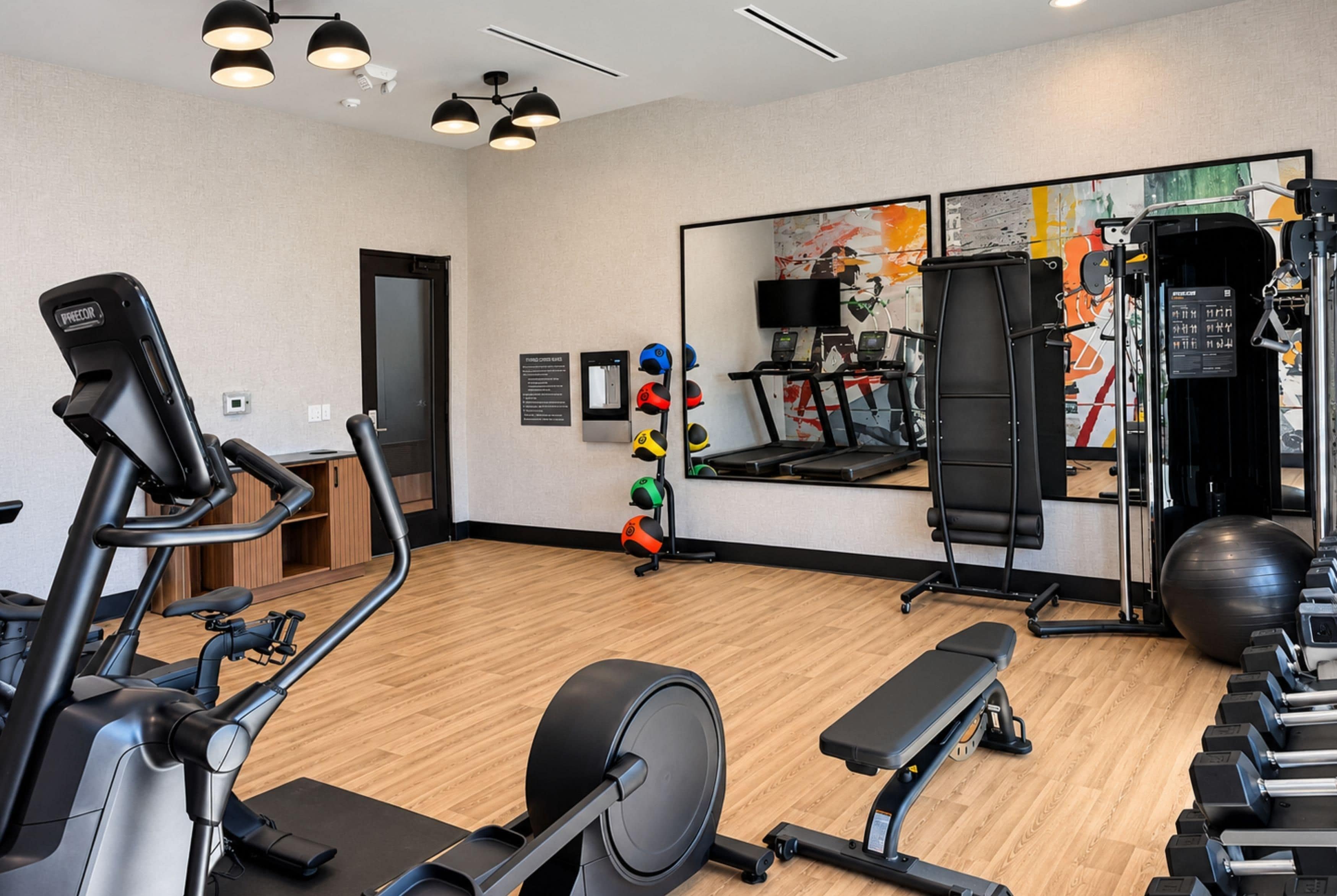 A gym with exercise equipment, a mirror, and a wall with artwork.