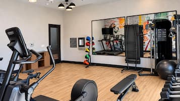 A gym with exercise equipment, a mirror, and a wall with artwork.