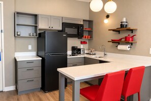 A compact kitchen with a refrigerator, microwave, coffee maker, and a small sink. - Hawthorn Extended Stay by Wyndham Central McKinney (McKinney)