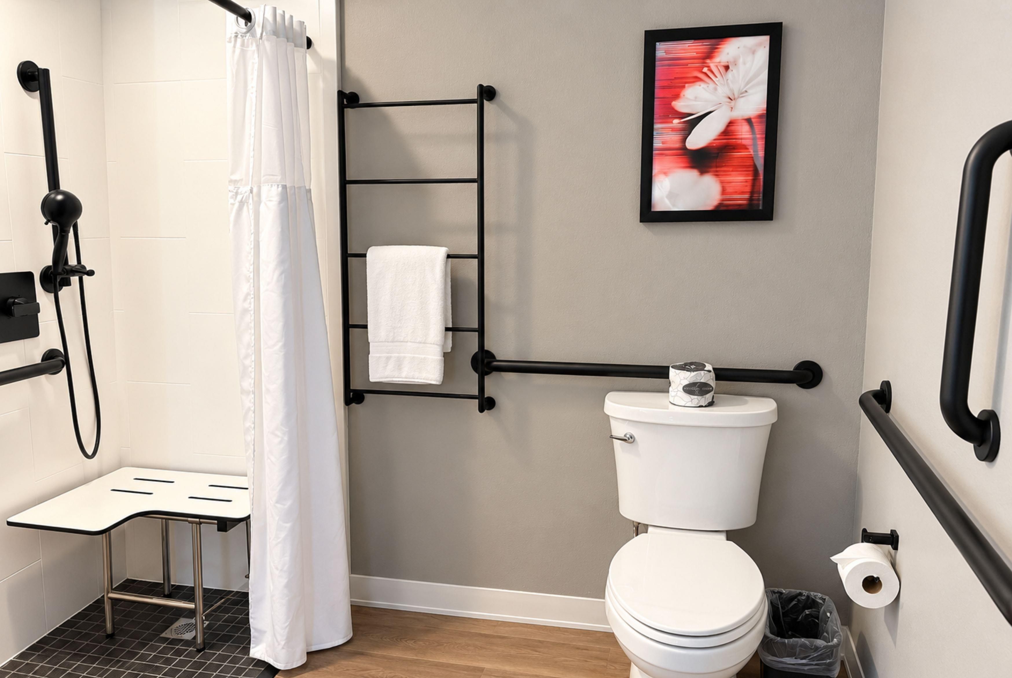 Une salle de bain moderne équipée d’une douche, de toilettes et d’un porte-serviettes.