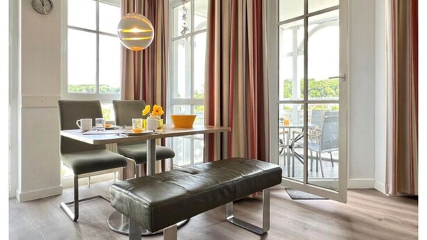 A modern dining area with a table, chairs, and a bench. - Holiday apartment with balcony and Ahoi discount (Sellin)