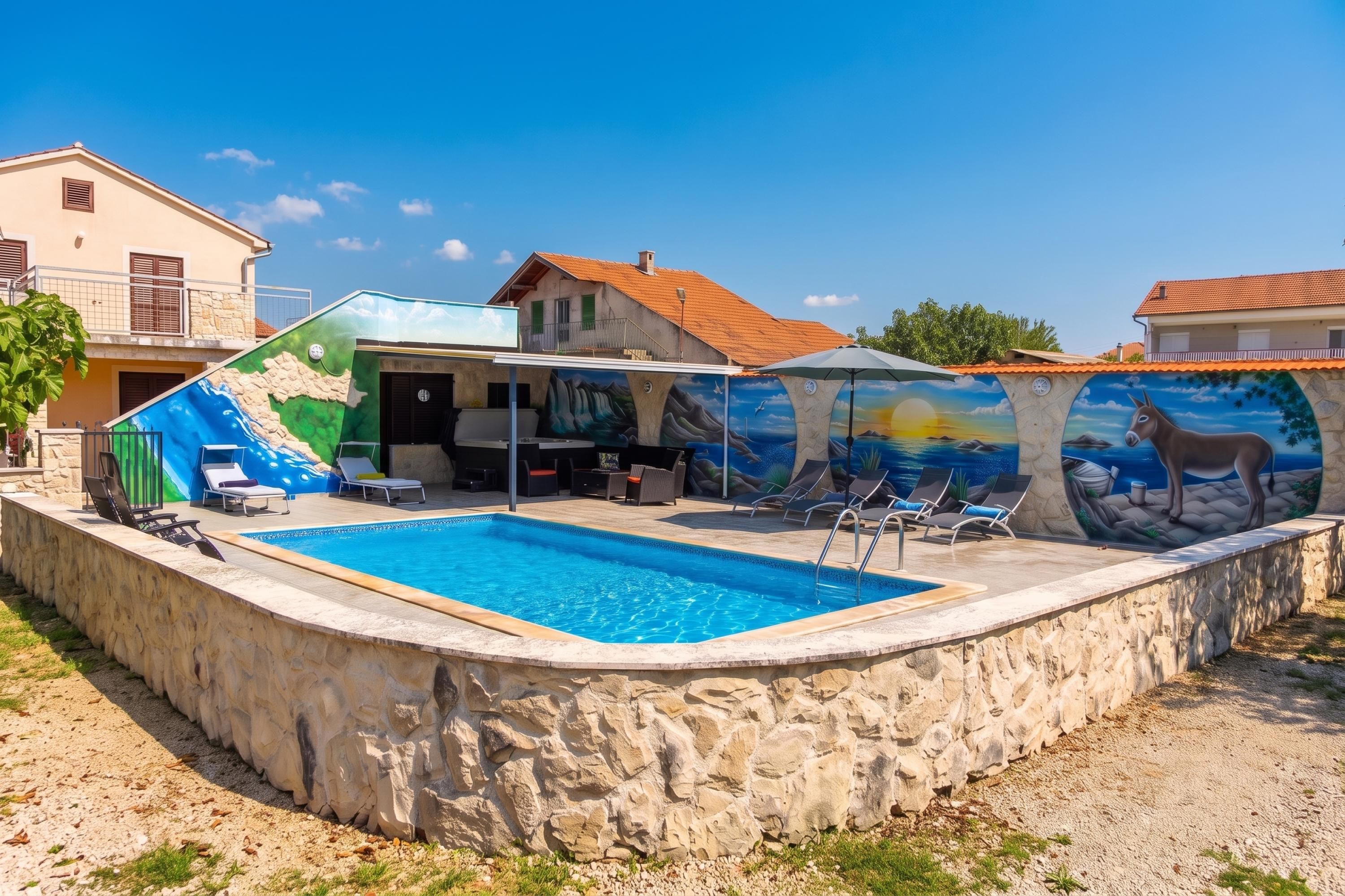 Une piscine dotée de chaises longues et dont les murs sont décorés d’une fresque.