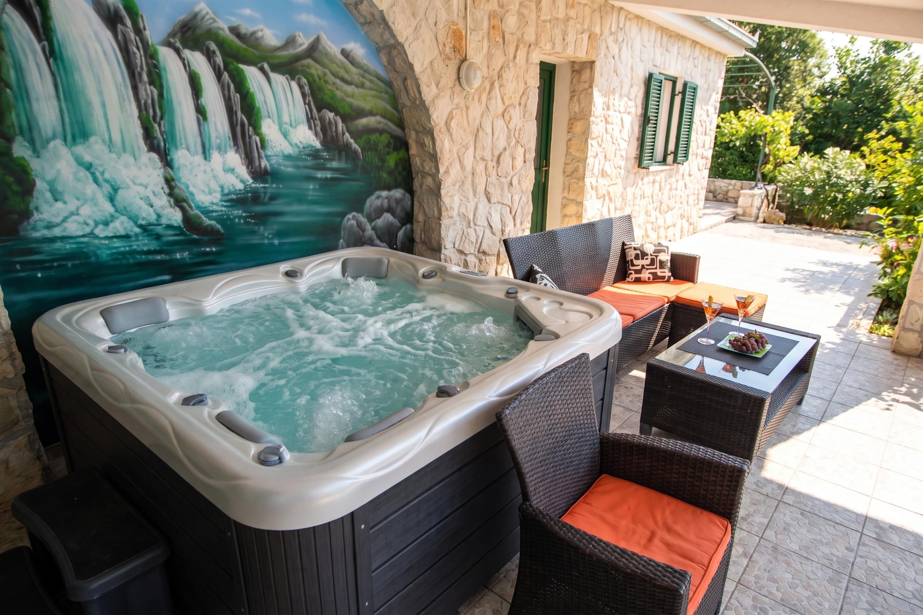 Un bain à remous agrémenté d’une fresque représentant une cascade, avec des sièges extérieurs et un mur en pierre.