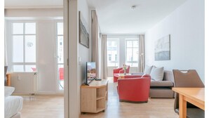 A modern living room with a sofa, a TV, and a wooden table. - Komfortable Ferienwohnung mit Balkon (Sellin)