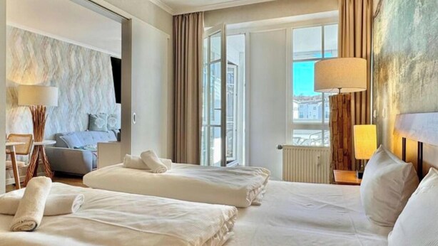 Ein Hotelzimmer mit zwei Betten, einem Schlafsofa, einem großen Fenster und Blick auf die Stadt.