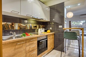 A modern kitchen with wooden cabinets, a built-in oven, and a dining area with a chair.