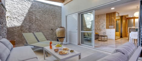 A modern interior with a stone wall, a dining area with a table set for two, and a sofa.