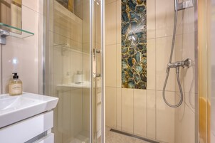 Un baño con cabina de ducha de vidrio, un lavabo blanco y un elegante revestimiento de azulejos.