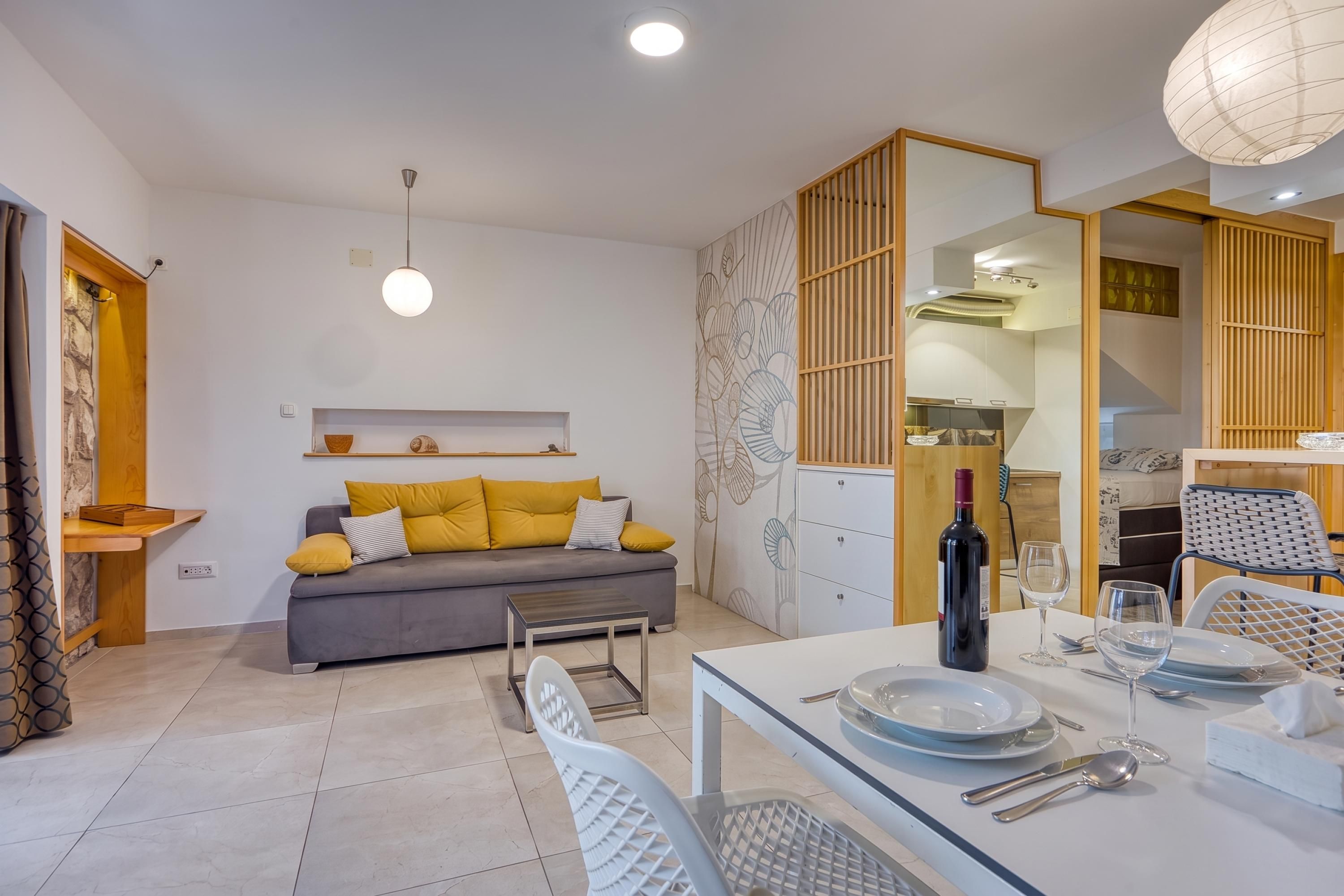 A modern living space with a sofa, dining table, and kitchen area.