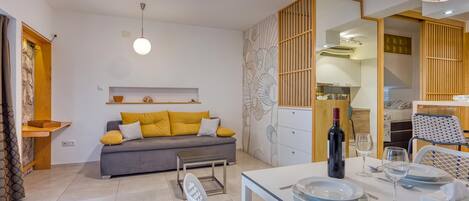 A modern living space with a sofa, dining table, and kitchen area.