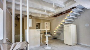Un interior moderno con una escalera, un refrigerador blanco y un taburete de bar.