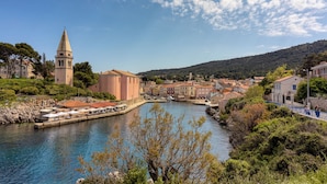 Un pueblo costero con una torre destacada, un río y una combinación de edificios tradicionales y modernos.