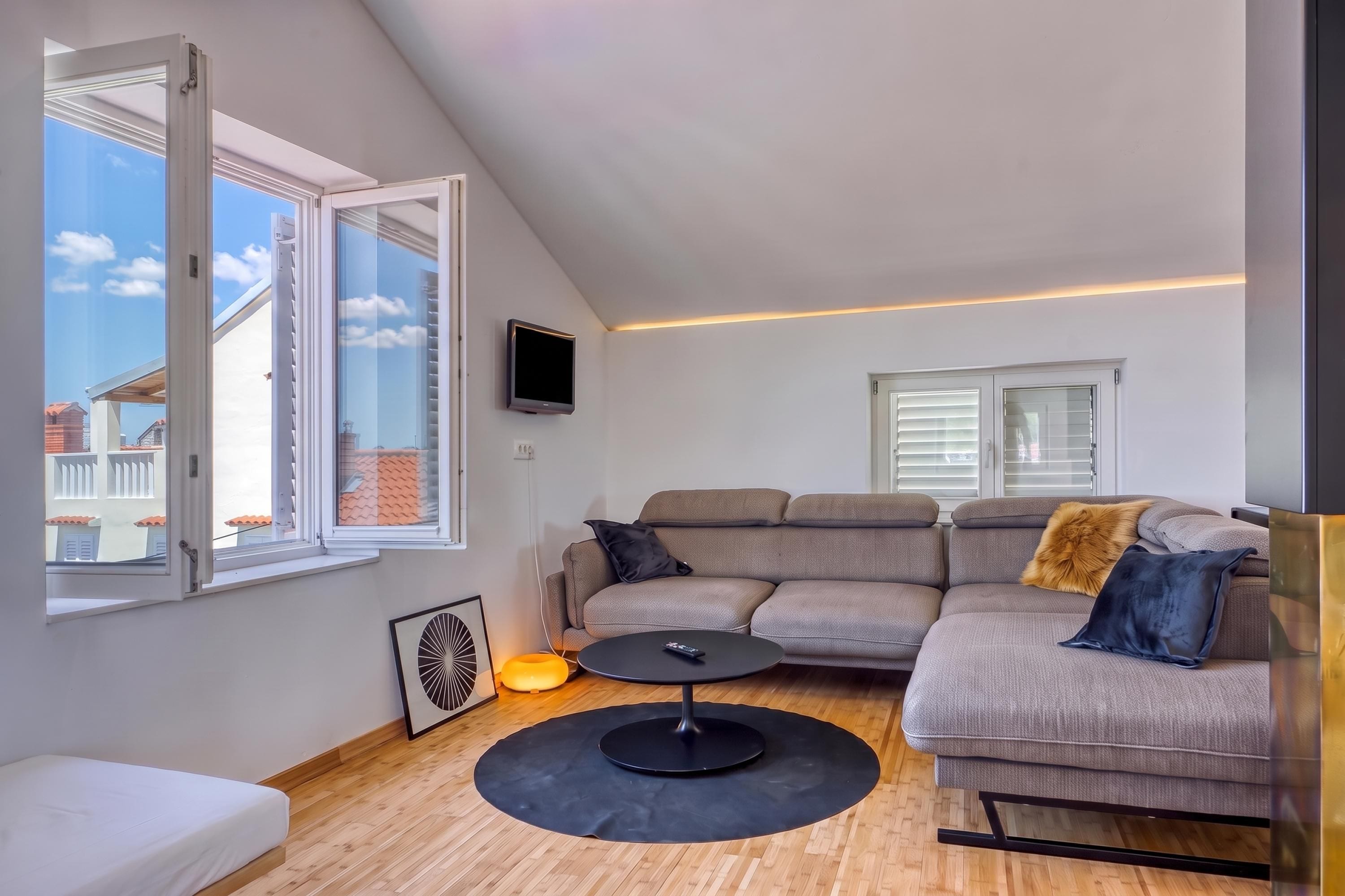 Una sala moderna con un sofá modular, una mesa de centro y un televisor montado en la pared.