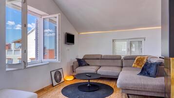 Una sala moderna con un sofá modular, una mesa de centro y un televisor montado en la pared.