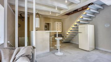 A modern interior with a staircase, a white refrigerator, and a bar stool.