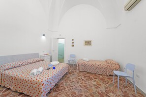 Ein Hotelzimmer mit zwei Betten, einem Sessel, einem kleinen Tisch und einer Tür zum Badezimmer.